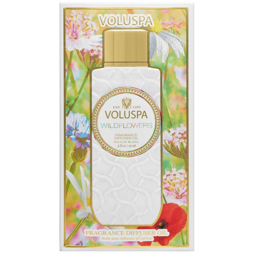 The Voluspa - Wildflowers Fragrance Diffuser Fragrance Oil bottle features a textured white surface, a shiny gold cap, and packaging with vibrant floral illustrations of native wildflowers, like poppies and daisies, alongside the brands signature decorative text.