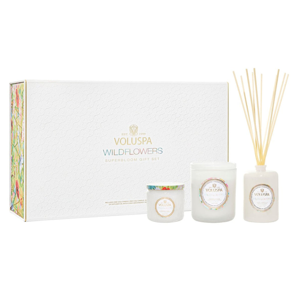 The Voluspa Wildflowers Superbloom Gift Set includes a white Wildflowers candle, a small Soft Citrus candle, and a reed diffuser, all beautifully arranged in front of a decorative box with Golden Poppy floral accents.