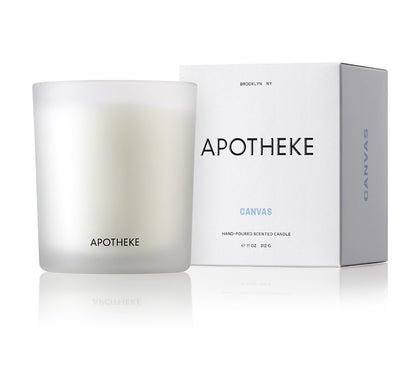 A frosted glass candle labeled Apotheke stands beside its matching box marked Canvas. The Apotheke - Canvas Classic Candle 10.5oz is a luxurious scented candle crafted from a soy wax blend, showcasing elegance and simplicity through its minimalist design.