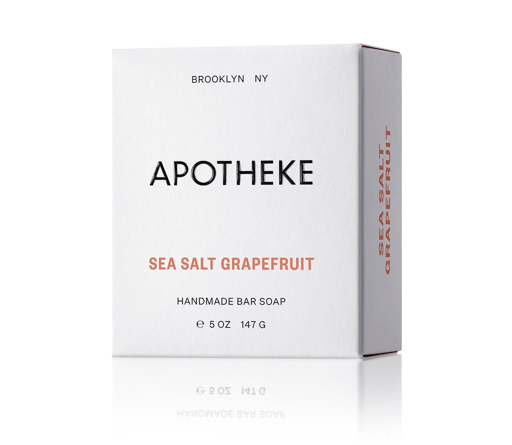 A white box of Apothekes Sea Salt Grapefruit Bar Soap showcases minimalist black and orange text. It details the weight (5 oz / 147 g) and Brooklyn, NY origin. The citrus fragrance is highlighted with Sea Salt Grapefruit on the side.