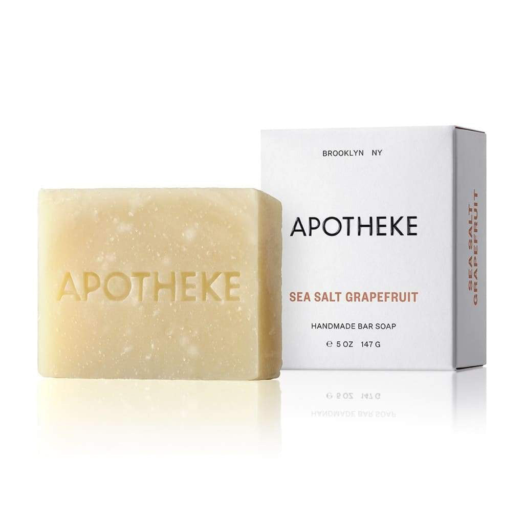 A beige Apotheke bar soap embossed with the brand name and labeled Sea Salt Grapefruit comes packaged in a BROOKLYN NY, APOTHEKE box. This plant-based 5 oz (147 g) soap offers a refreshing citrus scent.