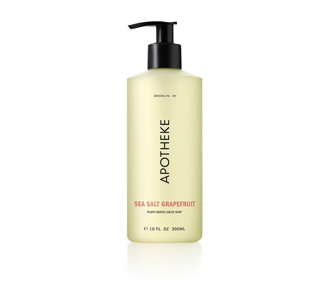 A 10 fl. oz. tall, translucent pale yellow bottle with a black pump features APOTHEKE in vertical black text and is labeled Sea Salt Grapefruit in red, enriched with aloe vera, describing it as a plant-based liquid soap.