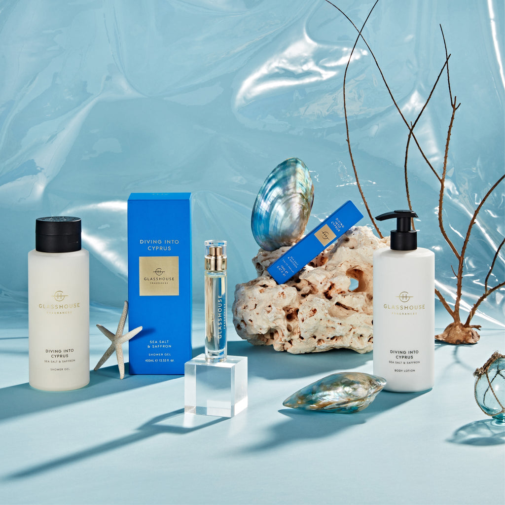 Glasshouse Fragrances Eau de Parfum 14ml - Diving Into Cyprus is displayed on a blue backdrop with seashells, coral, and a starfish.