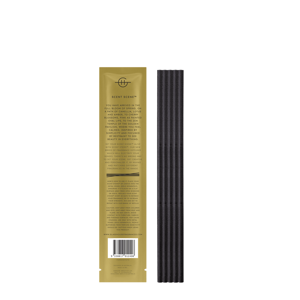 A tall, slender package displays a bundle of black incense sticks on the right and dark yellow-brown packaging on the left with a circular emblem reading Scent Stems, featuring CAMELLIA & LOTUS and a barcode at the bottom. Product: Glasshouse Fragrances - Replacement Scent Stems - Kyoto In Bloom.