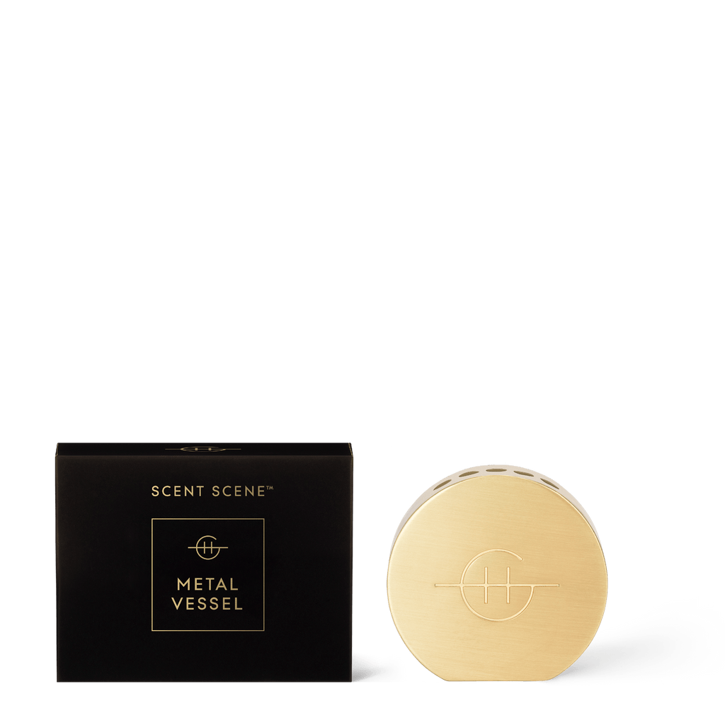 A black rectangular box labeled “Scent Scene Stand” by Glasshouse Fragrances stands beside a round, gold-toned Glasshouse Fragrances container, both set against a white background for an elegant fragrance display.