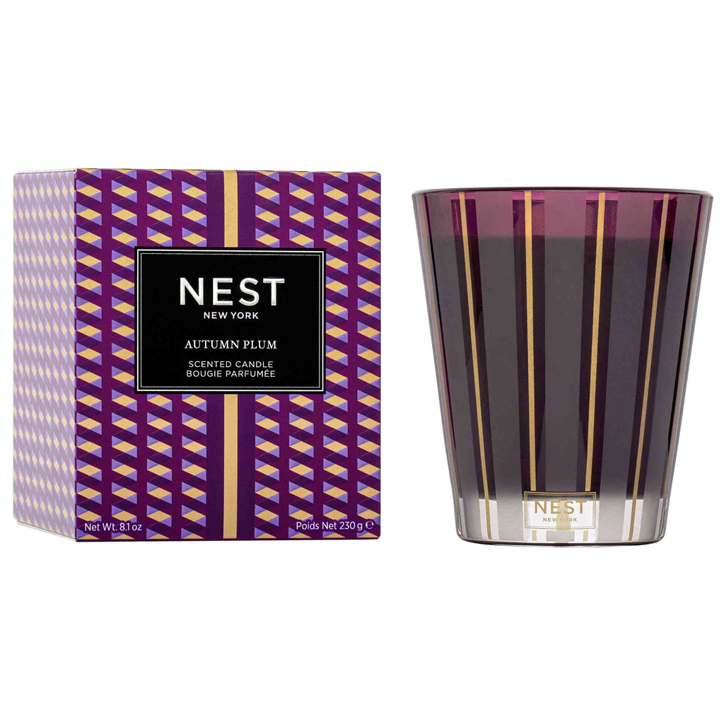 A Nest - Autumn Plum Classic Candle, in purple and gold stripes with a matching geometric box, stands out with its elegant Nest branding.