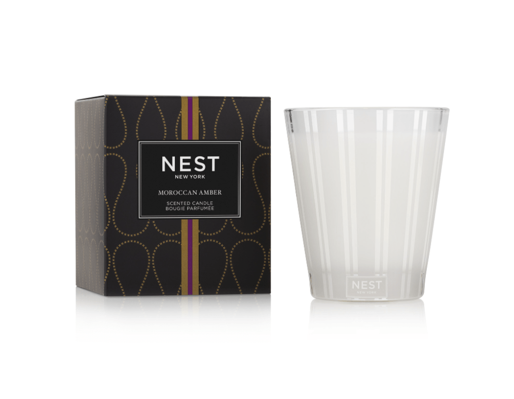 The Nest - Moroccan Amber Classic Candle features rich, woody amber notes in a modern frosted glass holder, paired with a decorative black and gold box for a luxurious fragranced candle experience.