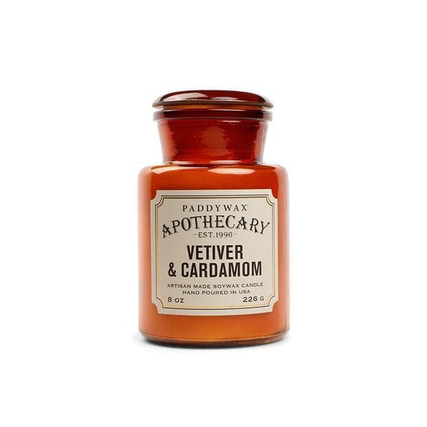 The Paddywax Apothecary Vetiver + Cardamom 8oz Candle features a vintage-inspired brown amber glass jar and cream label; this artisan, hand-poured home fragrance is crafted in the USA.