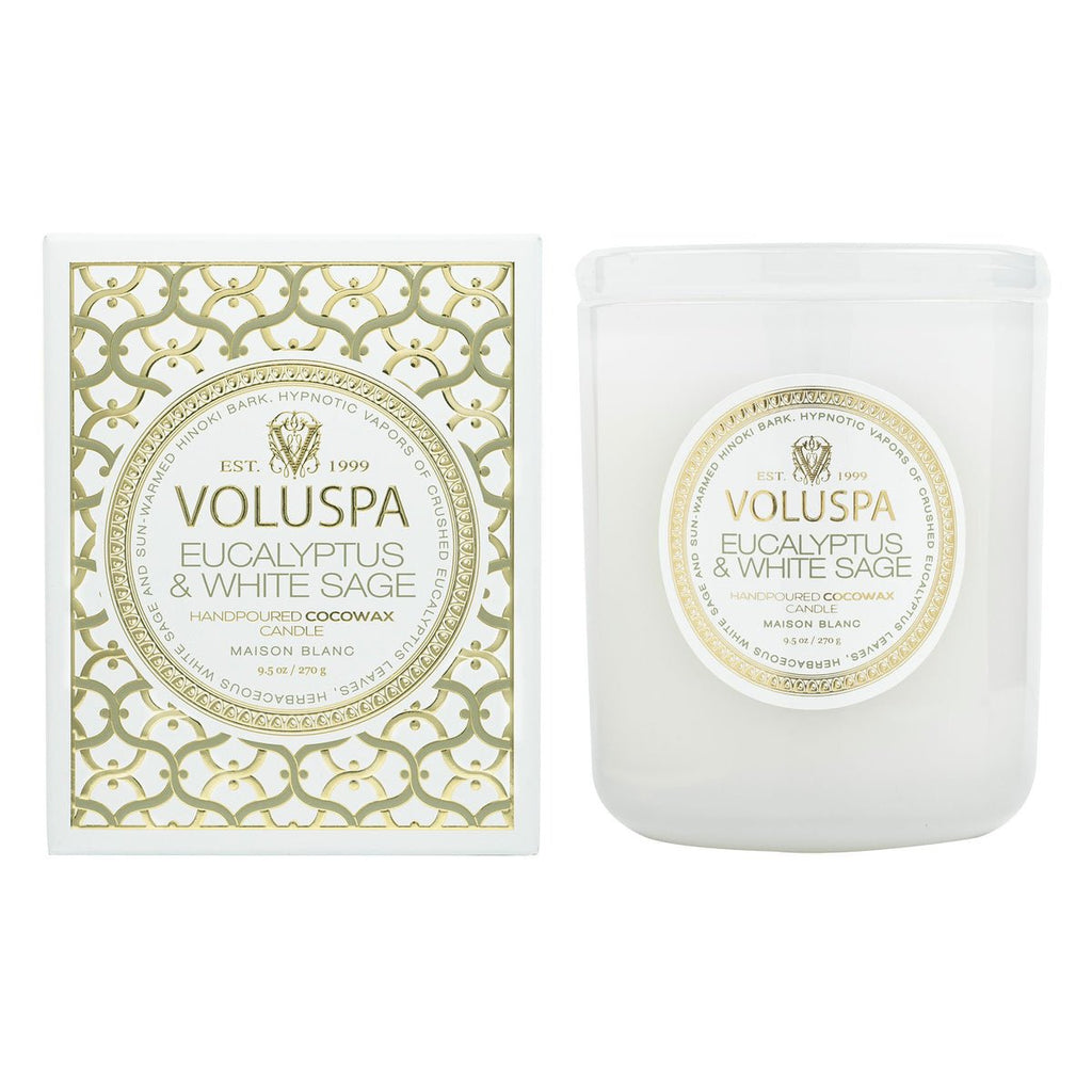 The Voluspa Eucalyptus and White Sage Classic Candle 9.5oz from the Maison Blanc collection features a luxurious coconut wax blend, elegantly presented in a white jar with a matching label. The candle comes in a decorative white box adorned with an intricate gold pattern.